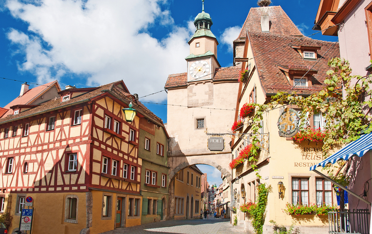 Historisches Stadttor und Fachwerkhäuser bei sonnigem Wetter.