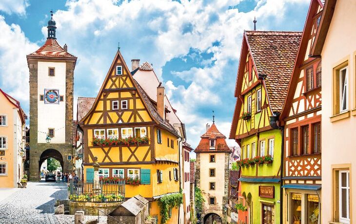Malerische Altstadt mit Fachwerkhäusern und einem mittelalterlichen Torbogen im Hintergrund.
