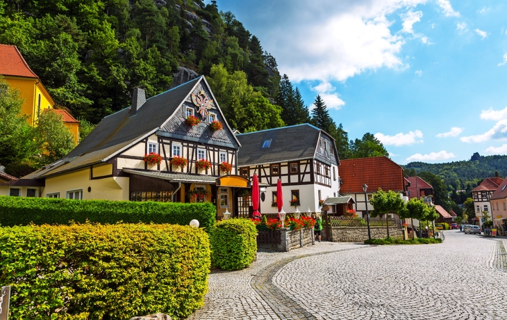 Fachwerkhaus und gepflasterte Straße in einem malerischen Dorf umgeben von Bäumen