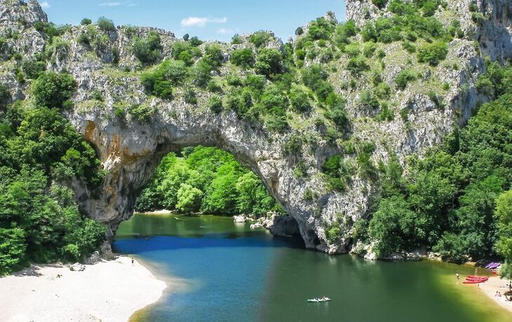 Steinbrücke über einem Fluss in einer grünen Landschaft.