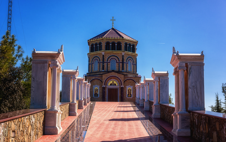 Kirche mit Säulengang und blauem Himmel im Hintergrund.