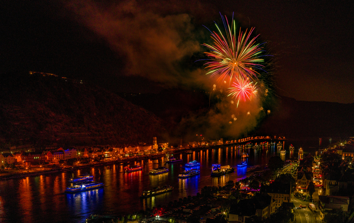 Feuerwerk über einem Fluss, beleuchtete Brücke bei Nacht.