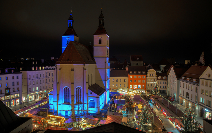 Nächtlicher Weihnachtsmarkt um eine beleuchtete Kirche.
