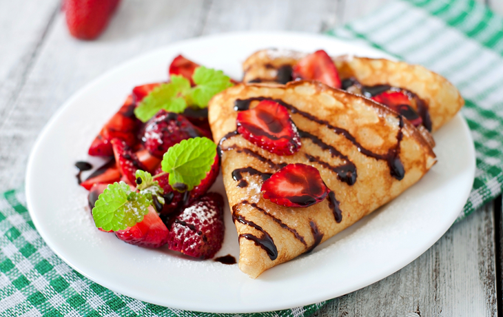 Pfannkuchen mit Erdbeeren und Schokolade verziert mit tadellosem Blatt