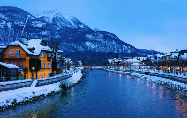 Verschneite Stadt mit Fluss und Berg im Hintergrund.