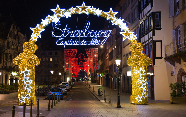 Festlich beleuchteter Torbogen in Straßburgs Altstadt bei Nacht.