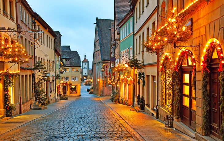 Eine festlich beleuchtete Altstadtstraße bei Abenddämmerung.