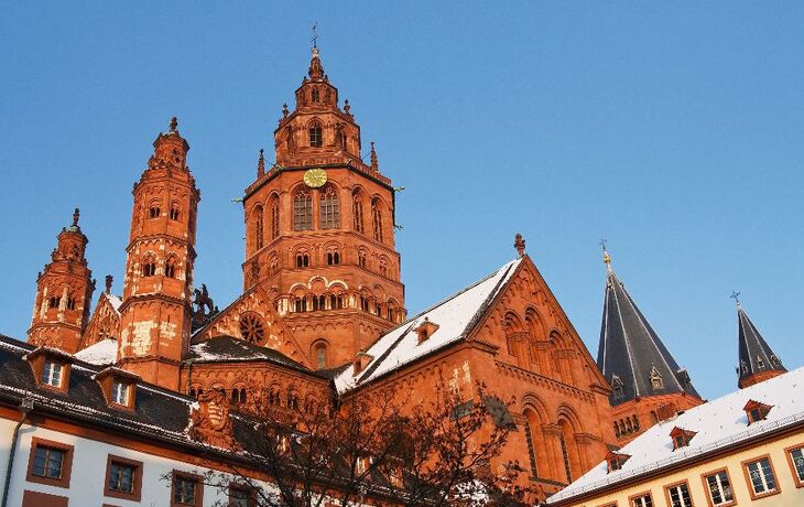 Mainzer Dom mit schneebedeckten Dächern, gotische Architektur, blauer Himmel im Hintergrund.