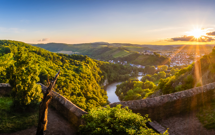 Panorama einer Landschaft mit Fluss und Sonnenuntergang.