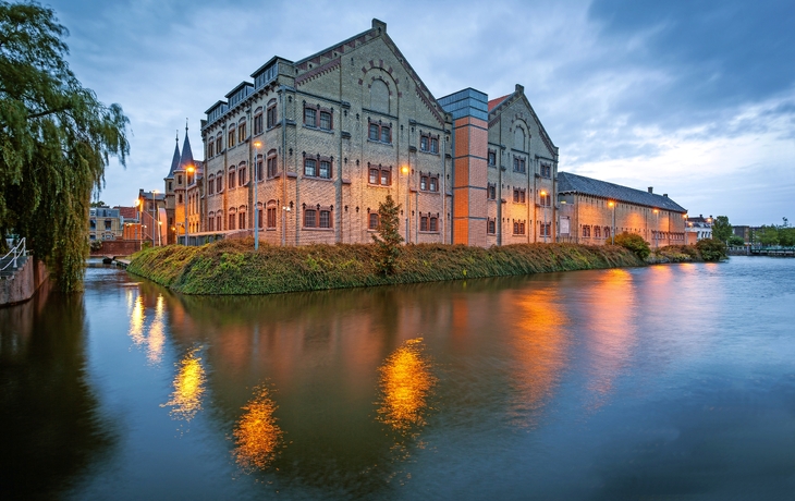 Historisches Gebäude bei Abenddämmerung, das sich im Wasser spiegelt.