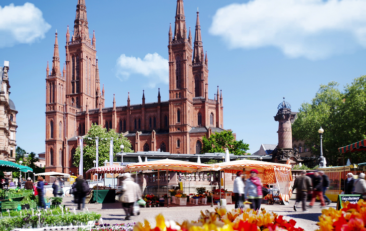 Marktplatz mit gotischer Kirche und Verkaufsständen im Freien.
