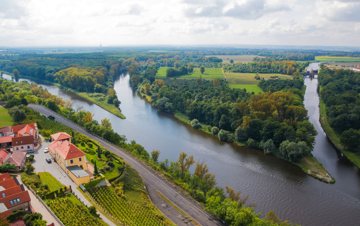Flusslandschaft mit Häusern und Wäldern aus der Vogelperspektive.