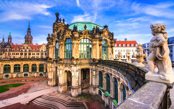 Barockgebäude mit Skulpturen im Zwinger, Dresden, unter blauem Himmel.