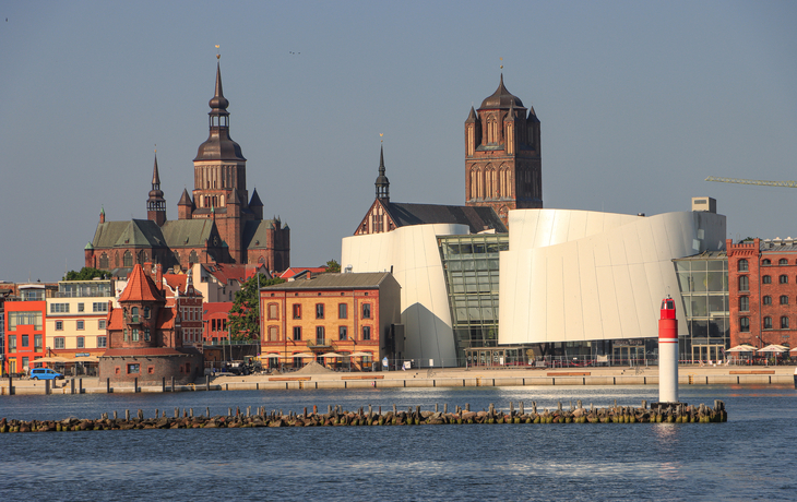 Stadtpanorama von Stralsund mit historischem Hafen und modernen Gebäuden am Wasser.