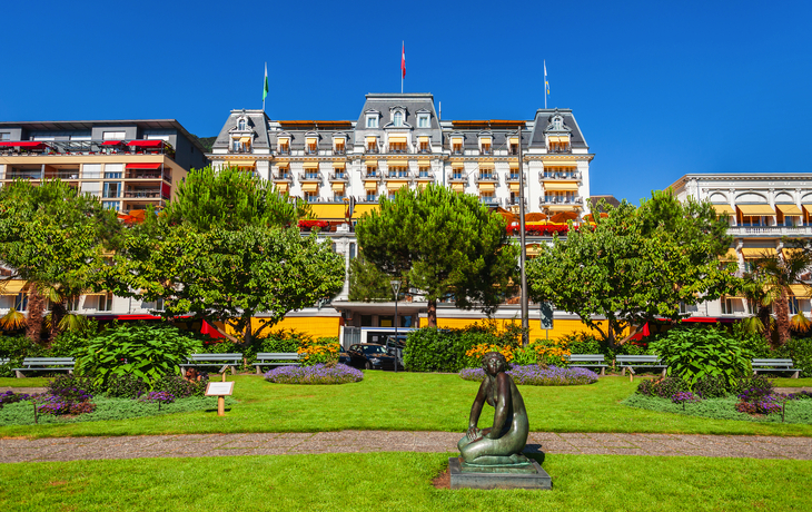 Hotelgebäude im Hintergrund, Statue im Vordergrund, parkähnliche Umgebung