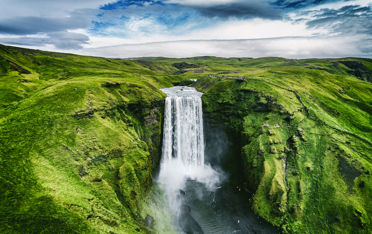 Mächtiger Wasserfall in grüner Landschaft unter bewölktem Himmel