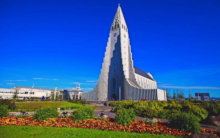Eine moderne Kirche mit markanter, hoher Fassade vor blauem Himmel.