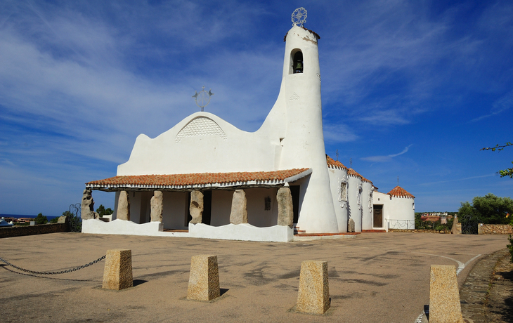 Weiße Kirche mit auffälliger Architektur unter blauem Himmel.