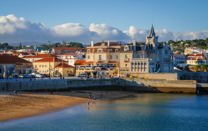Strand mit historischen Gebäuden und Wolken im Hintergrund.
