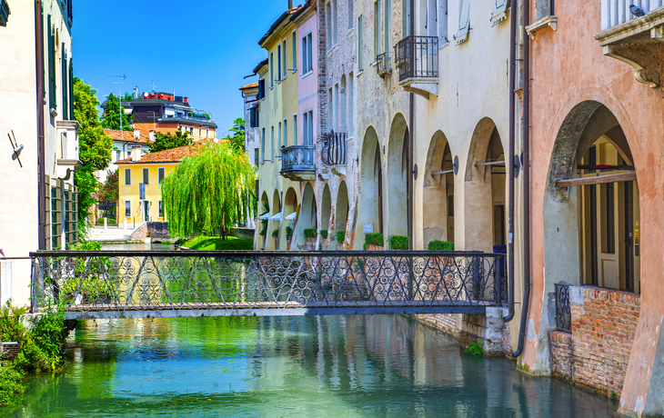 Bunte Häuser an einem Kanal mit Brücke in einer italienischen Stadt.