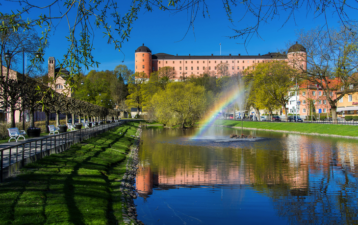 Schloss mit Regenbogen und Parklandschaft im Frühling.