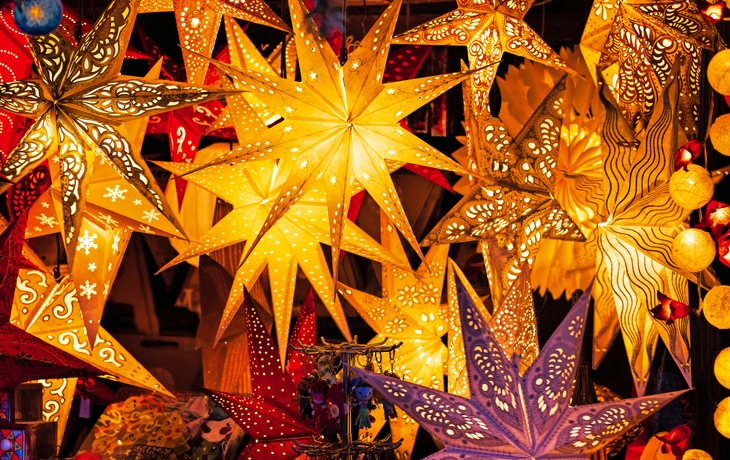 Bunte leuchtende Papiersterne auf einem Weihnachtsmarkt.