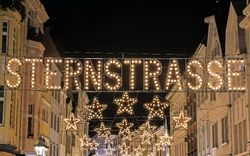 Beleuchtete Einkaufsstraße mit Stern-Dekorationen und Schriftzug 