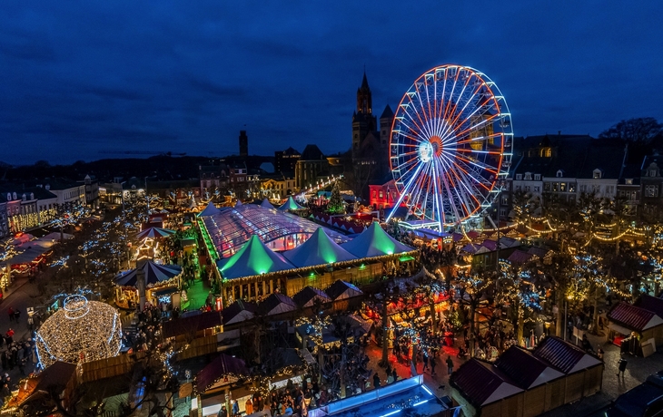 Blick auf bunten Weihnachtsmarkt mit Riesenrad bei Nacht in Maastricht.